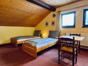 two beds in a room with a table and a chair at Myslivna Harrachov in Harrachov