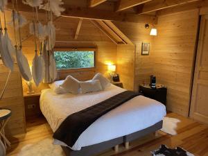 ein Schlafzimmer mit einem Bett in einer Holzhütte in der Unterkunft Cabane perchée luxe avec jacuzzi Domaine du Marais Maisse in Maisse