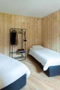 two beds in a room with wooden walls at Wome house con idromassaggio in Campo