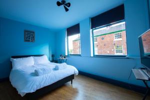 a blue bedroom with a bed and a window at The Crown & Anchor in Manchester