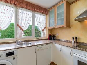 a kitchen with white cabinets and a sink and two windows at Holiday Home La Joya by Interhome in Boó de Piélagos