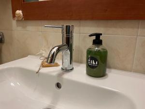 - un lavabo avec distributeur de savon et une bouteille de savon dans l'établissement AppArt 24 city center parking and Sea, à Lignano Sabbiadoro