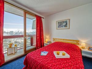 een slaapkamer met een rood bed en een groot raam bij Apartment Lunik Orion-41 by Interhome in Le Corbier