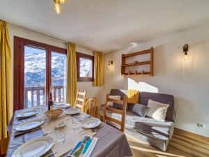 a dining room with a table and a couch at Apartment Balcons D'Olympie-3 by Interhome in Les Menuires