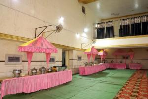 a large room with pink tables and umbrellas at Hotel Kumkum Chhaya in Panna