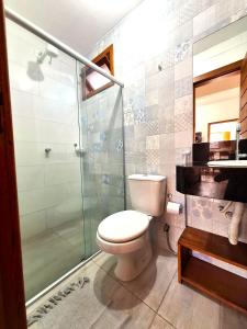 a bathroom with a toilet and a glass shower at Hospedaria Mucugê - na principal rua da cidade, Rua do Mucugê - Arraial d'Ajuda in Arraial d'Ajuda