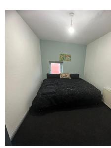 een slaapkamer met een zwart bed in een kamer bij Samco flat in Ashton-in-Makerfield