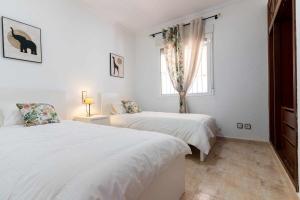 a white bedroom with two beds and a window at rentafive - Nuevo - A/A - Barbacoa - Tenis in Santa Pola +41 photos