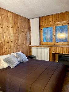 1 dormitorio con cama, paredes y ventanas de madera en Cataleya Laceno en Villaggio Laceno