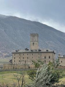 een oud gebouw met een klokkentoren in een veld bij Maison Marcel Sarre in Aosta