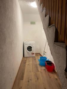 a laundry room with a washing machine and buckets on a wooden floor at Maison Marcel Sarre in Aosta