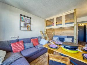 a living room with a blue couch and a table at Studio Soyouz Vanguard-100 by Interhome in Le Corbier