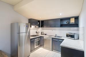 una cocina con electrodomésticos de acero inoxidable y armarios azules en Bay Village Resort Dunsborough en Dunsborough
