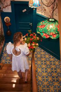 Una niña vestida de blanco bajando las escaleras con flores. en Domaine Bohème I art de vivre, en Guebwiller