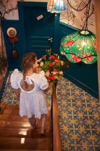 Ein kleines Mädchen in weißem Kleid, das mit Blumen die Treppe hinuntergeht. in der Unterkunft Domaine Bohème I art de vivre in Guebwiller