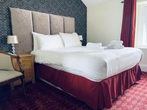 a large bed in a hotel room with a chair at Merrion Hotel in Llandudno