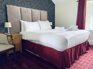 uma cama grande num quarto de hotel com uma cadeira em Merrion Hotel em Llandudno