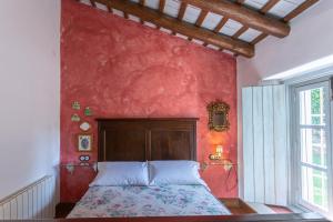 a bedroom with a red wall with a bed at Cortijo Chacón in Cazalla de la Sierra