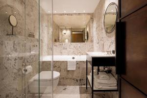 a bathroom with a tub and a toilet and a sink at Hypernym Hotel & Suites in Copenhagen