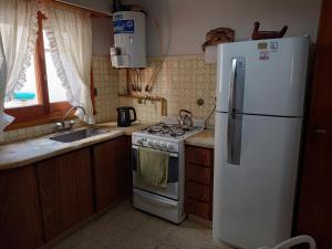 a kitchen with a white refrigerator and a stove at Chalet Claromeco in Balneario Claromecó