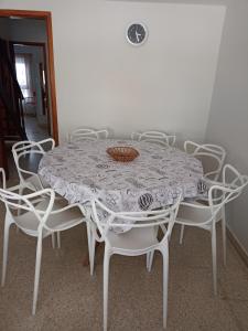 una mesa con sillas blancas alrededor con una cesta encima en Chalet Claromeco en Balneario Claromecó