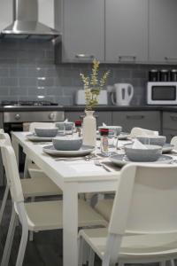 un tavolo bianco con sedie e piatti bianchi in cucina di Isimi luxurious 4 bed 4 en -suite house Cumbria a Barrow in Furness