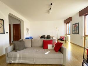 een woonkamer met een grijze bank met rode kussens bij Ca' Beuys In The Kitchen Apartment in Mestre