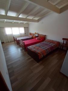 two beds in a room with wooden floors at Chalet Claromeco in Balneario Claromecó