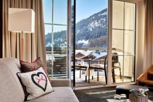 a living room with a couch and a large window at Panoramahotel Oberjoch in Bad Hindelang