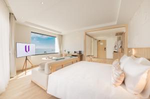 a bedroom with a white bed and a flat screen tv at U Hua Hin in Phetchaburi