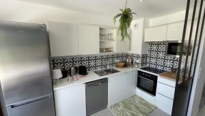 a kitchen with white cabinets and black and white tiles at Le Clos Du Moulin 1 - Maison et jardin, proche Avignon, en Provence in Entraigues-sur-la-Sorgue