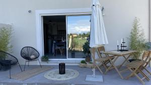 een patio met een tafel, een parasol en stoelen bij Le Clos Du Moulin 1 - Maison et jardin, proche Avignon, en Provence in Entraigues-sur-la-Sorgue