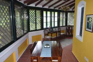 a dining room with a table and chairs and windows at The Bungalow in Bangalore