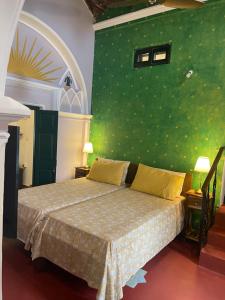 a bedroom with a bed with a green wall at The Bungalow in Bangalore