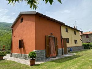 una pequeña casa con una pared de color naranja en La casina rossa della fornace en Cutigliano