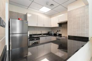 a kitchen with a stainless steel refrigerator and white cabinets at LARBI Luxurious 1BR in Polo Residence in Dubai