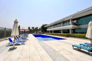 a row of chairs and umbrellas next to a pool at LARBI Luxurious 1BR in Polo Residence in Dubai