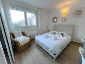 een slaapkamer met een bed, een stoel en een raam bij Le Côtier in Blériot-Plage