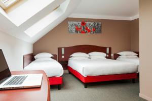 アラスにあるHôtel Arras Sudのベッドルーム1室(ベッド3台、ノートパソコン付きのデスク付)
