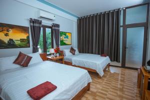 um quarto de hotel com duas camas e uma janela em Phong Nha Cherish House em Phong Nha