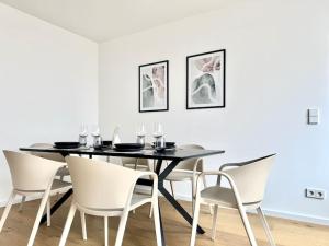 a dining room with a black table and white chairs at Luxuriös - Dachterrasse - Küche in Forchheim