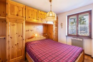 1 dormitorio con 1 cama con manta roja a cuadros en Lagorai 16 Villaggio Veronza, en Carano