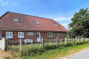 a small red brick house with a wooden fence at Diekhüser Rodenäs in Rodenäs