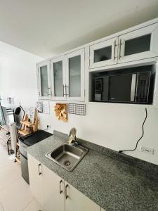 eine Küche mit Spüle und weißen Schränken in der Unterkunft Tagaytay Staycation 1Br w/ Balcony at SMDC Cool Suites in Tagaytay