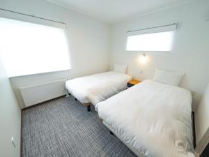 two beds in a room with two windows at AIR FURANO in Furano