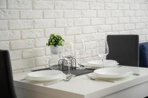 a white table with plates and glasses on it at Black and White Apartment Close to the River in Wrocław by Renters in Wrocław