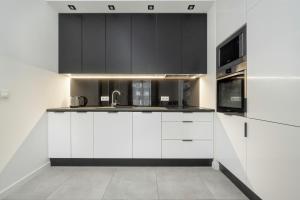 a kitchen with black and white cabinets and a sink at Black and White Apartment Close to the River in Wrocław by Renters in Wrocław