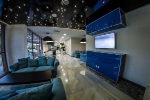 a living room with blue couches and a flat screen tv at Premier Fort Beach Hotel in Sveti Vlas