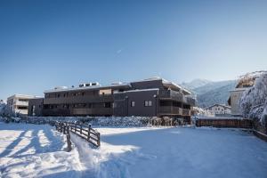 un grande edificio con neve sul terreno di fronte ad esso di Alp Living Apartments Self-Check In a Innsbruck