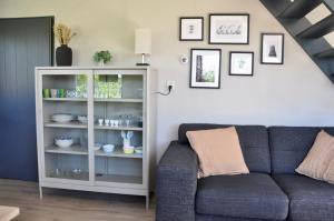 - un salon avec un canapé et une étagère avec de la vaisselle dans l'établissement Crocus, à Sint Maartensvlotbrug